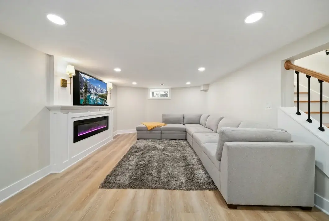 Finished basement family room with sectional sofa, electric fireplace and recessed lighting
