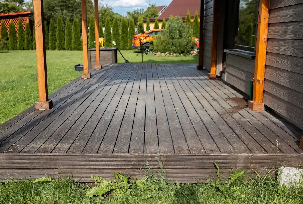 Dark-stained wood deck with timber posts overlooking a green backyard