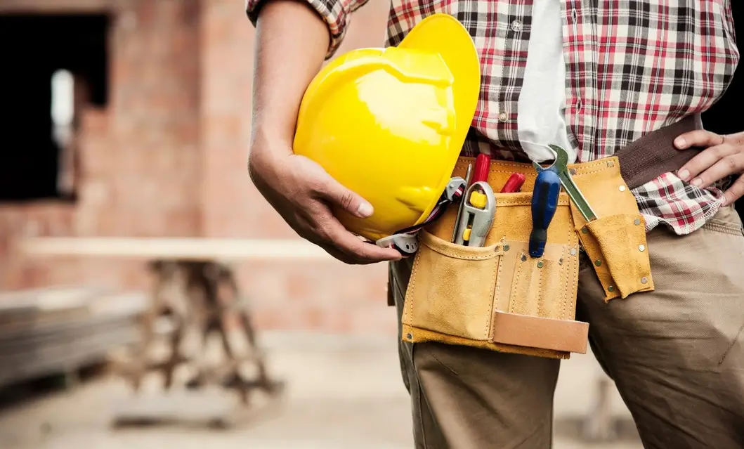 Victory Construction remodeling company professional holding safety helmet and construction tools at a residential project.