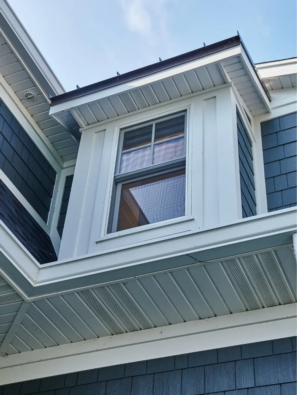 Professional siding installation by Victory Construction featuring blue exterior siding, white trim, soffits, and window detailing